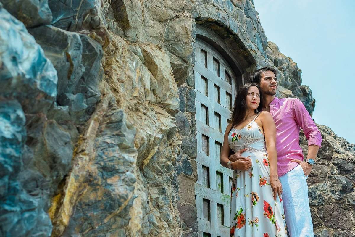 Pareja apoyada en un muro de roca junto a una puerta de madera