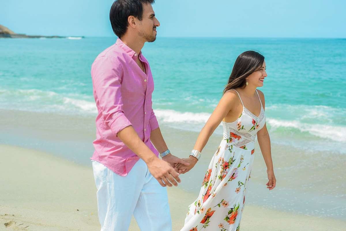 Pareja paseando de la mano por la orilla del mar