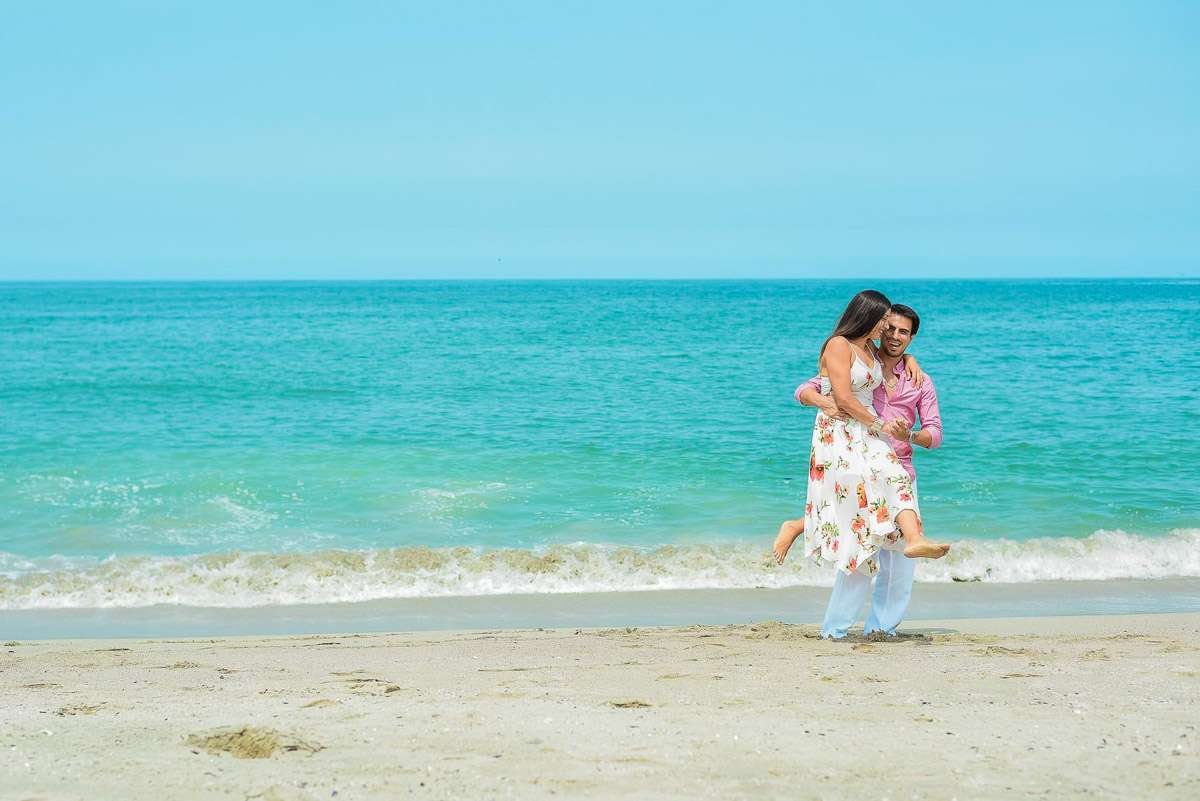 Pareja abrazada entre las olas, con el mar turquesa de fondo