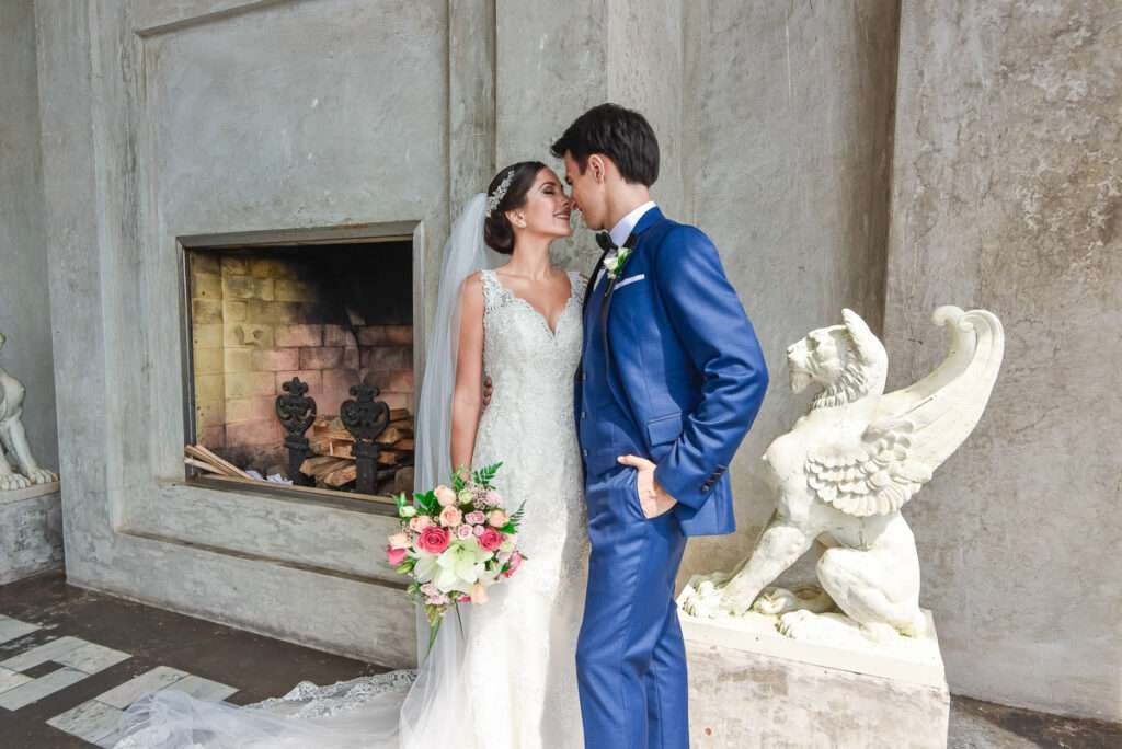 Novios junto a una chimenea de piedra y una escultura de grifo en una finca
