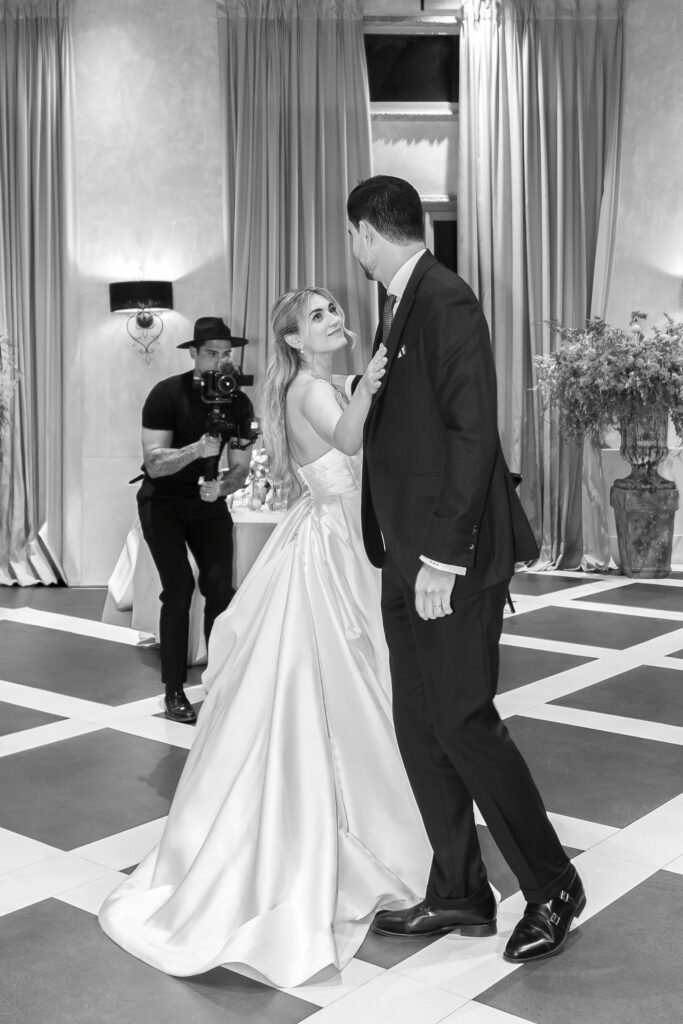 Primer baile de los novios en blanco y negro, con el videógrafo grabando al fondo