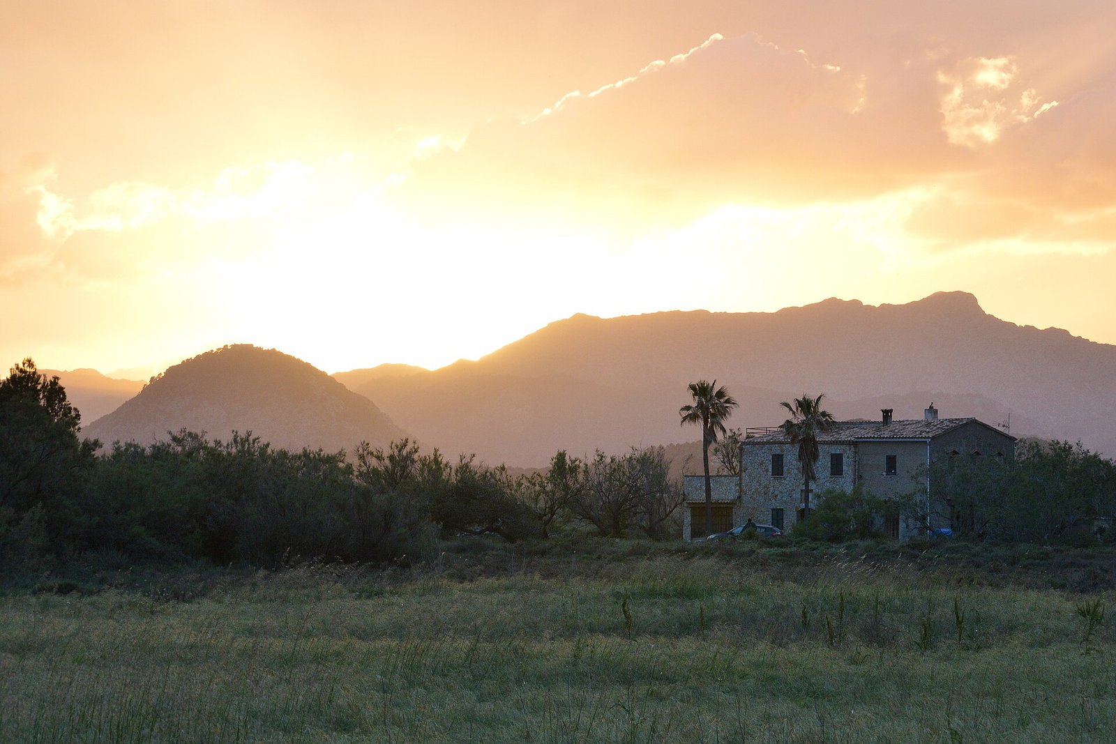 Casa de piedra mallorquina al atardecer, con la Serra de Tramuntana al fondo