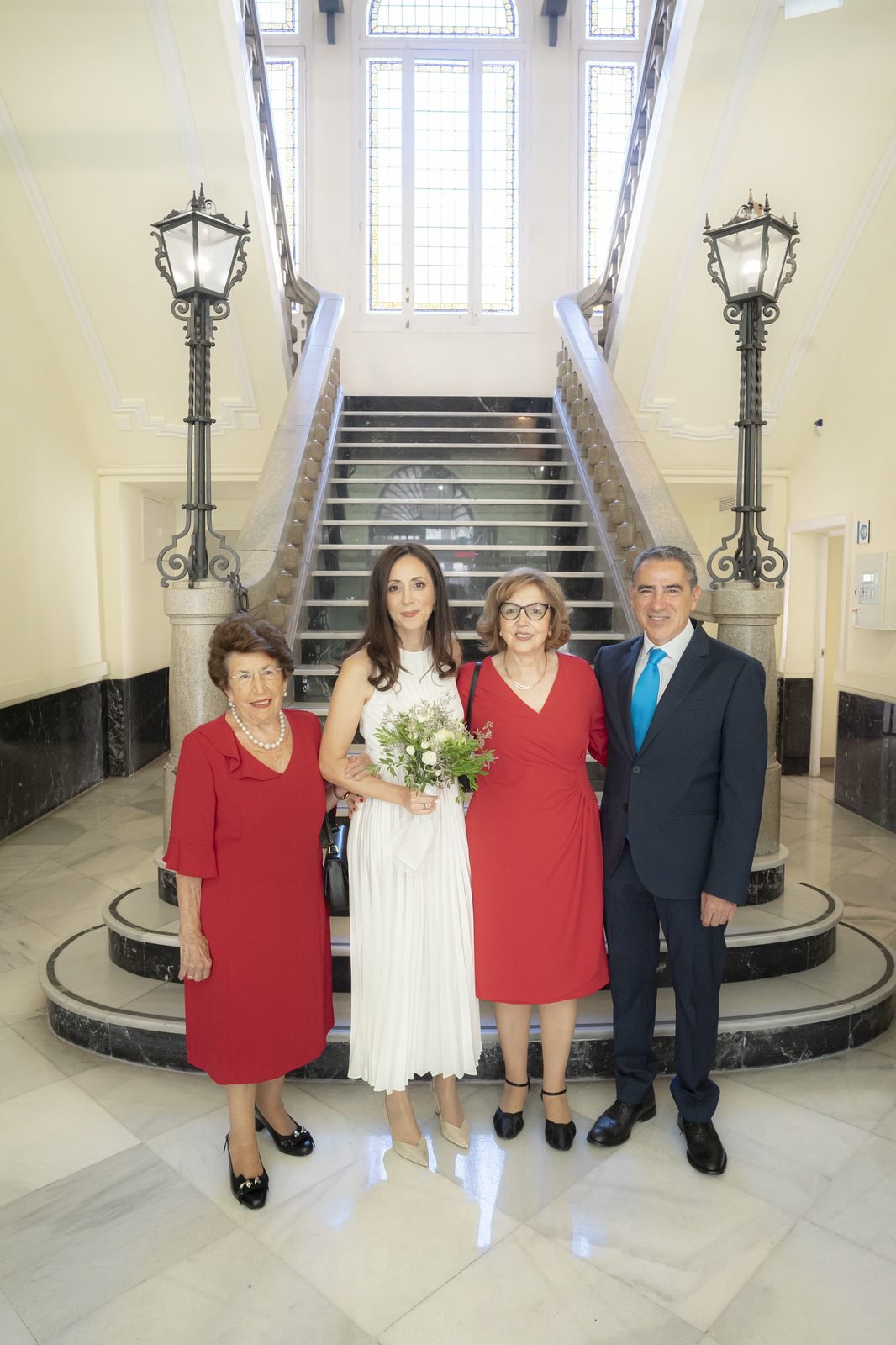 Los novios y su familia en la escalera de mármol del Hotel Santo Domingo, entre las farolas del vestíbulo