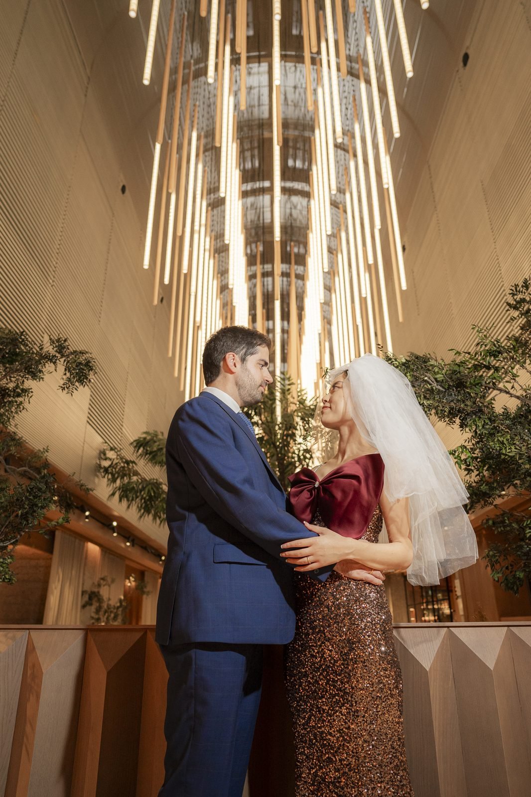 Los novios abrazados bajo la instalación de luces colgantes del NH Eurobuilding