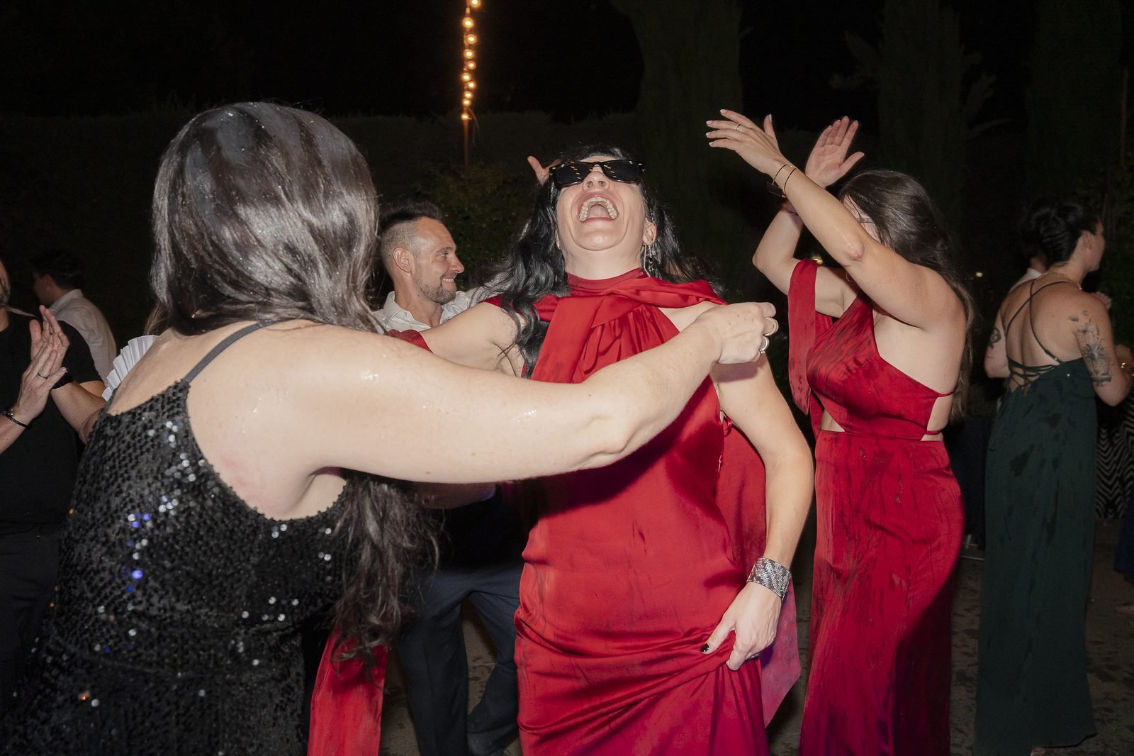 Invitadas bailando y riéndose de noche en el jardín de Finca Solimpar, bajo guirnaldas de luces